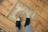 A person stands on the vintage distressed Oushak rug, demonstrating its small scale as a mat.