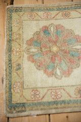 Corner of a distressed Oushak mat showing its floral vine and outer zig-zag borders.