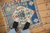 Distressed Oushak corner with pale blue field, red floral beige border, and fringe.