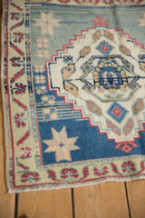 Distressed Oushak rug corner showing muted blue, red, beige floral border and field.