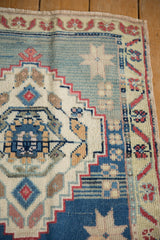 Fringed corner of vintage Oushak rug showing dusty blue field and faded floral border.