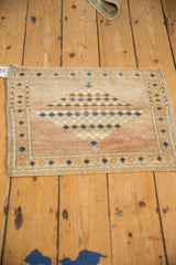 Distressed Oushak rug mat corner, featuring dusty mauve pile and blue seed border.