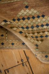 Vintage distressed Oushak rug's curled edge, showing textured pile and diamond pattern in dusty blue.