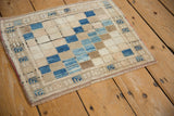 Close-up of distressed Oushak rug mat showing diagonal blue, ivory, beige squares.