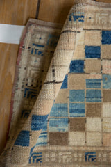Rolled textured pile with blue and beige squares on a vintage distressed Oushak rug.