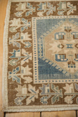 Vintage distressed Oushak rug corner showing textured pile, dusty blue, beige geometric motifs.