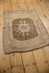 An angled view of a vintage Turkish Kars mat with distressed, low-pile texture and earthy tones.