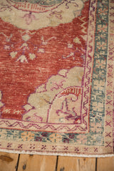 Distressed cherry red field, ivory spandrel, and dusty teal border on a vintage Oushak rug corner.
