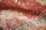 Distressed cherry red field showing knot heads, an ivory border with violet vine motif, and dusty teal details on a vintage Oushak rug.