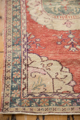 Distressed Oushak runner corner, cherry red field, ivory spandrel, dusty teal border, pile wear.