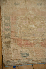 Distressed pile of the Oushak rug showing sand, faded raspberry, and dusty teal hues.