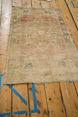 Vintage distressed Oushak rug with textured fringe and faded floral border.