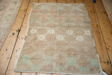 Distressed Oushak rug corner with pale mint green fern blossom design and abrashed ground.