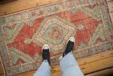 Soft, distressed texture of a vintage Oushak runner with time-softened red and seafoam green colors.