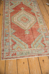 High-angle view of a distressed Oushak runner with a red and seafoam green stepped medallion.