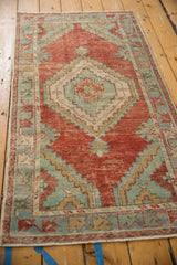 Angled overhead view of a distressed Oushak runner's cherry red field and seafoam green medallion.