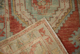 Folded corner of a vintage Oushak rug revealing its hand-knotted pile and woven foundation.