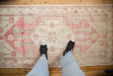 Distressed Oushak runner with soft pink, ivory, and faded blue hues, showcasing its worn texture.