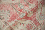 Distressed vintage Turkish Oushak rug texture, revealing faded pink, ivory, and soft turquoise tones.