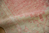 Hand-knotted texture of a distressed Oushak rug showing mostly even wear and low pile.