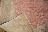 Folded corner of a distressed Oushak rug showing its hand-knotted foundation and weave.