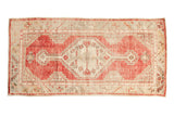 Vintage distressed Oushak runner with a geometric stepped medallion in soft red, ivory, and beige.
