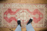 Scale and worn texture of a distressed vintage Oushak rug runner shown underfoot.