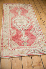 Angled view of a distressed Oushak runner, showing its time-softened red and ivory geometric pattern.