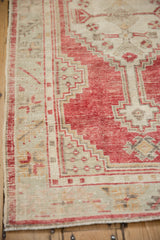Geometric serrated leaf and floral border with worn texture on a vintage Oushak runner.