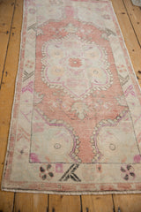 The distressed texture and low pile of a vintage Oushak runner shown from an angular perspective.