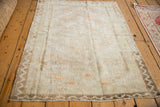 Perspective view of a distressed Tulu rug showing its shaggy pile and coffee brown zig-zag border.
