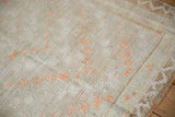 Angled view of the distressed texture on a vintage Tulu rug showing low pile and tangerine accents.
