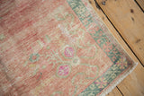 Worn corner of a vintage Oushak runner with dusty teal borders and rose floral spandrels.