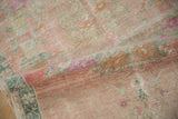 Softly folded vintage Oushak runner showing the abrashed pink field and distressed, low-pile texture.