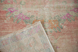 A folded corner of the distressed Oushak rug reveals its hand-knotted wool foundation.