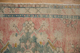 Distressed pile texture of vintage Oushak rug, dusty rose, ivory, and teal floral motifs.