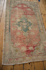 Visible distressed texture of vintage Oushak rug with faded dusty rose and teal.