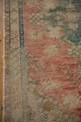 Distressed Oushak rug's side selvage, showing knot heads, muted dusty rose, teal, and ivory patterns.