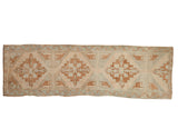 Vintage distressed Oushak runner rug, repeating medallions in muted ivory, copper, and seafoam green.
