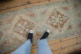 Oushak rug runner with distressed geometric patterns in ivory, seafoam, and copper.