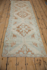 Distressed Oushak runner's geometric border with faded seafoam green and pale coffee brown.