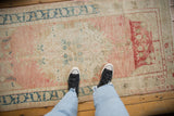Distressed Oushak runner featuring dusty rose ground, muted floral pattern, and teal border.