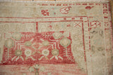 Distressed vintage Oushak rug corner, showing faded rose and ivory cloudband floral vines.