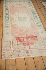 Distressed vintage Oushak rug runner with a dusty rose abrashed field and ivory corner spandrel featuring floral vines, alongside a dusty teal border.