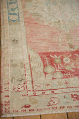 Distressed Oushak rug detail: dusty rose abrash, ivory ground, worn floral border.