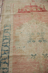 Vintage distressed Oushak runner showing low pile, dusty rose and ivory floral motifs.