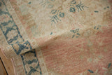 Distressed vintage Oushak runner's folded pile reveals dusty rose, teal border, and wear.