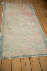 Angled view of a distressed Oushak runner showcasing its soft patina and faded floral pattern.