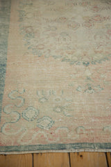Distressed, low-pile texture of a vintage Oushak runner with dusty teal and rose meandering vines.