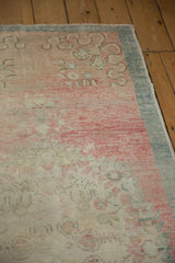 Thick teal border framing the abrashed dusty rose field of a vintage Oushak rug runner.
